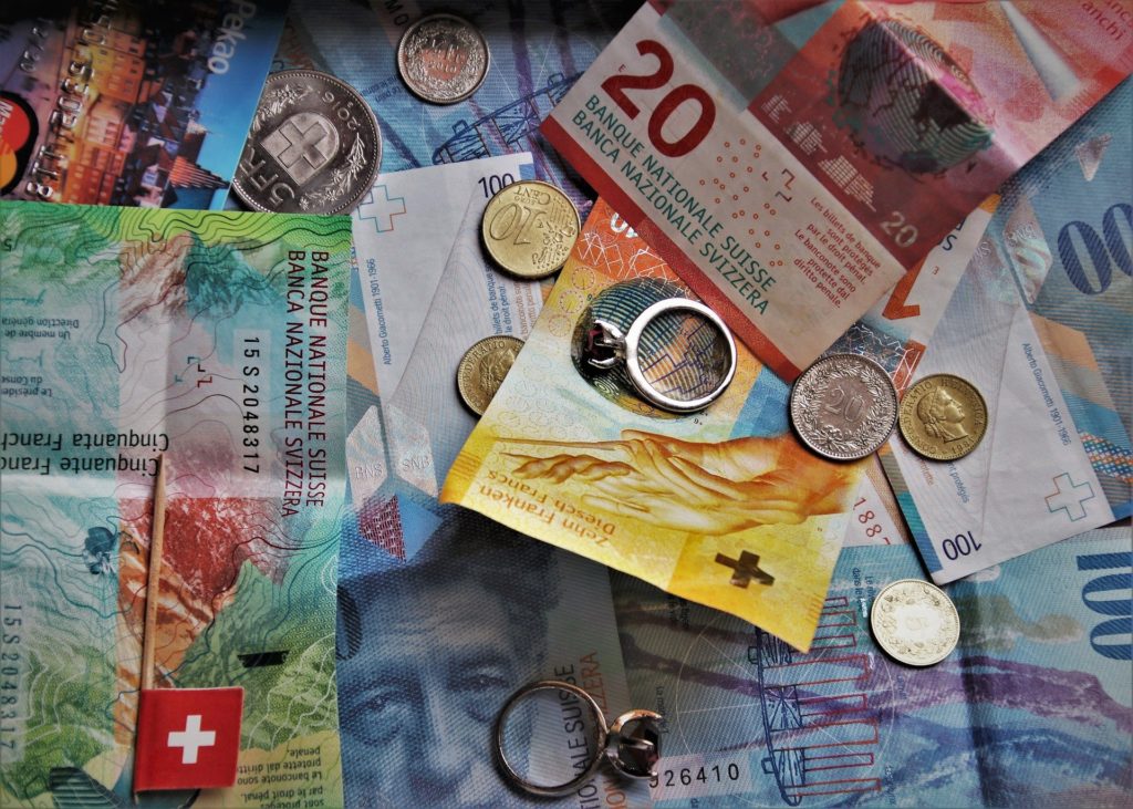 Billets de 50, 20 et 10 francs suisses éparses sur une table avec quelques pièces de monnaie.